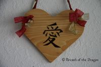 heart-shaped plaque burned with kanji symbol for LOVE with red and gold raffia ribbons, pyrography by Sunfire